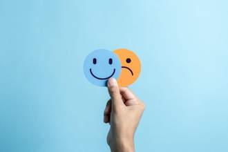 hands holding sad face hiding or behind happy smiley face