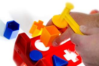 hands trying to hammer a square block into a circle cutout