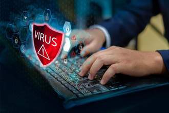 hands typing on computer as a red virus shield pops up