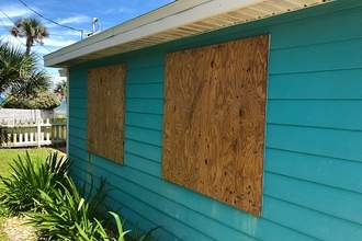 house with boards nailed over windows before storm