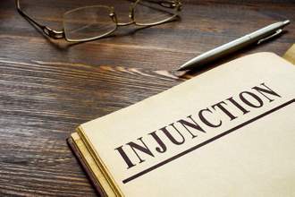 inunction word printed on page with a pen sitting beside it