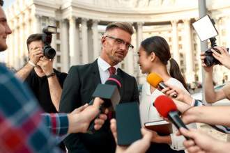 journalists conducting interview of a politician with advisor speaking into his ear