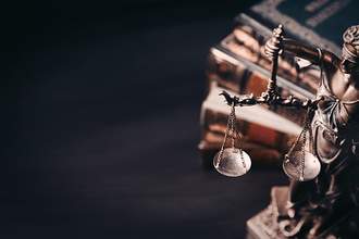 justice holding scale next to law books