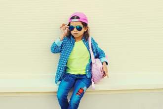 kid looking relaxed and uninterested as they adjust their sunglasses