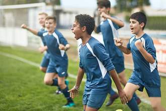 kids on a soccer team cheering a goal