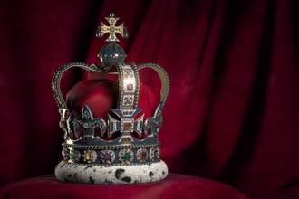 kings crown sitting on a red velvet cushion