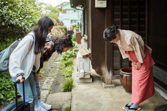 landlady greeting female guests outside ryokan