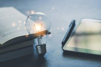 lit light bulb next to books