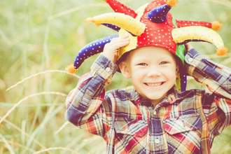 little boy smiling at the camera wearing a joker hat