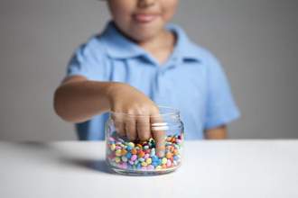 little boy taking candy from a jar