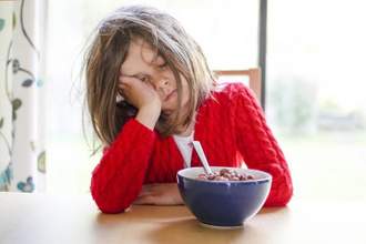 little girl looking disheveled while trying to eat breakfast