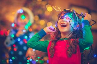 little girl playing with christmas lights