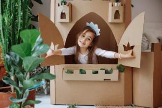 little girl pretending to be a princess in a cardboard castle in her family room