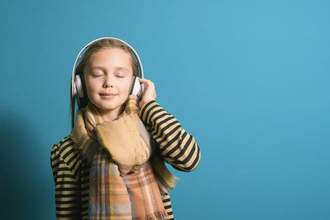 little girl slightly smiling with her eyes closed while listening to music
