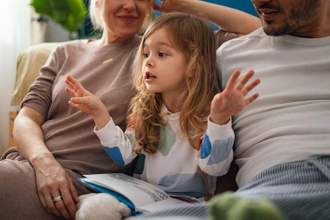 little girl talking up a storm while sitting besides her parents