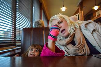little girl with shoe off sticking her foot in moms eye