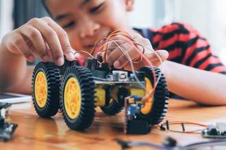 little kid having fun working on a robotic car
