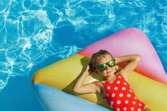 little kid relaxing on a floaty in a pool