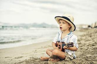 little kid singing and playing the guitar at the beach