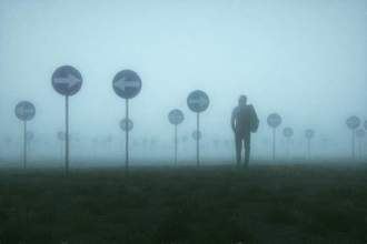 lost and confused businessman walking in a field