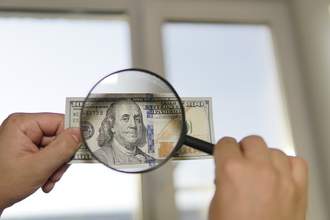 magnifying glass over hundred dollar bill