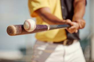 male baseball player at bat hitting a baseball head on