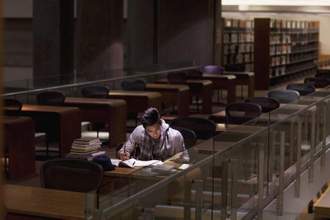 male student looking intently at his books while studying in his school library