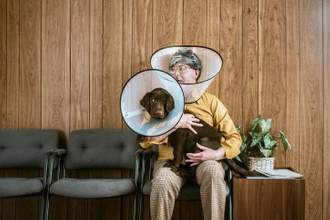 man at veterinarian wearing dog cone with their dog