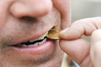 man biting a coin to see if its genuine