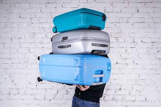 man carrying too many suitcases