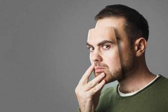 man holding a mask of emotion over his true facial feelings