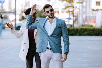 man holding up his hand waving away the person standing behind him