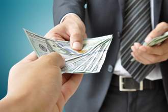man in a business suit handing over hundred dollar bills to a customer