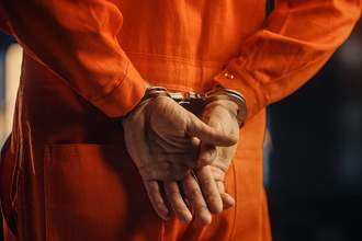 man in handcuffs and orange jumpsuit