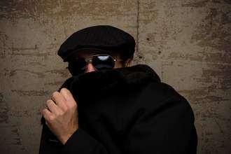 man in sunglasses pulling collar over face