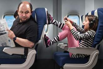man looking back at the annoying child sitting behind him on the airplane