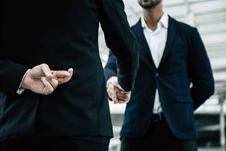 man making business deal while holding one hand with fingers crossed behind back