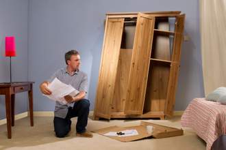 man putting together crooked cabinet