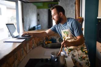 man quickly looking at an online recipe while trying to cook