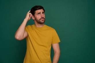 man scratching head wondering on green background