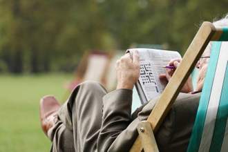 man sitting in deckchair outside doing crossword