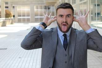 man sticking tongue out and wagging hands by ears