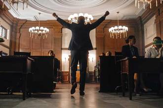 man triumphantly walking out of the courtroom with his arms raised in the air
