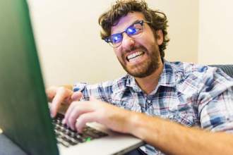 man typing on his computer angrily