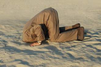 man wearing a suit putting his head in the sand