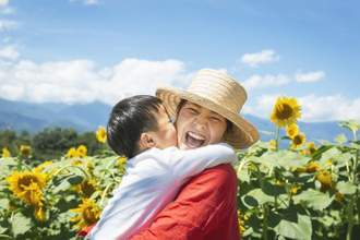 mother and son laughing together in a garden of sunflowers