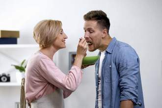 mother babying her son by feeding him