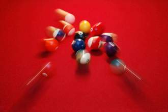 motion blur of pool balls scattering on a red pool table