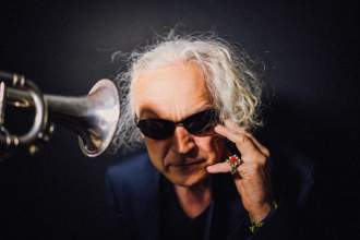 musician listening to a trumpet right by his ears