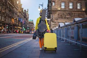 musician with his guitar and suitcase walking down the street